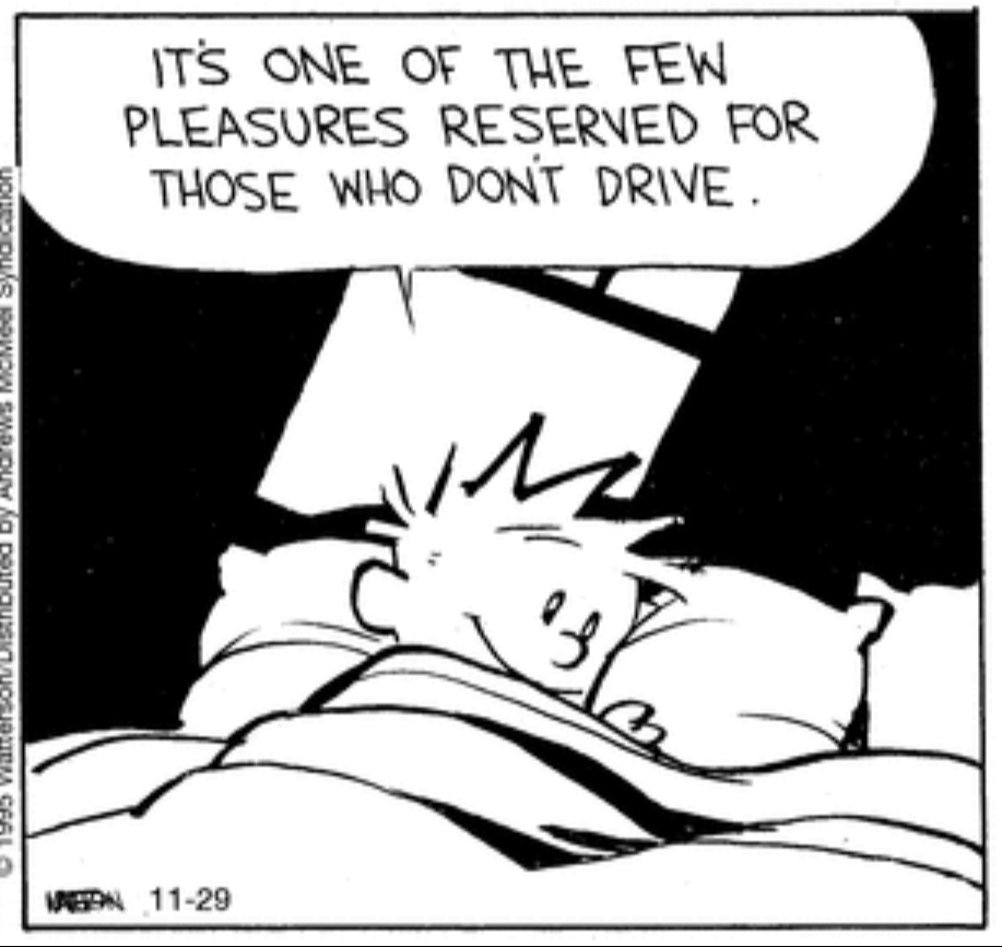 Calvin (from Calvin and Hobbes) curled up in bed with a smile on his face, saying “It’s one of the few pleasures reserved for those who don’t drive.”